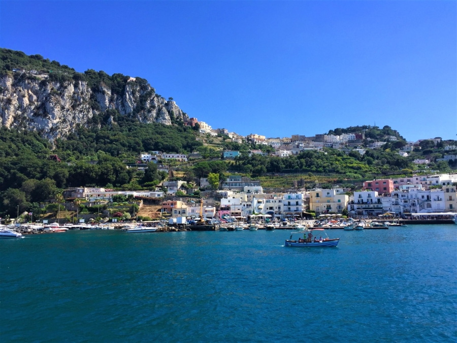 Visiting Capri, Italy – arriving by ferry at Marina Grande with colorful houses, cliffs, and boats along the Bay of Naples.