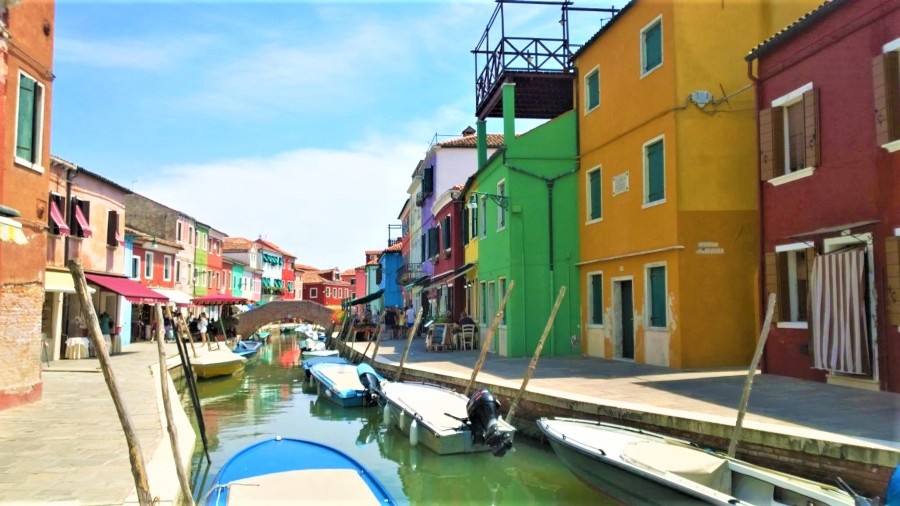 Colorful houses and boats along the canal viewed from Tre Ponti bridge in Burano, Italy