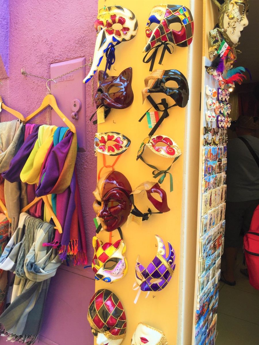 Handcrafted Venetian masks and colorful scarves on display in a Burano boutique, Italy