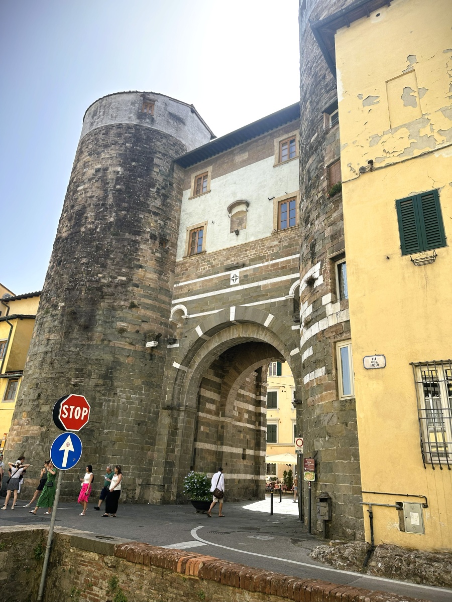 Porta di San Gervasio, the medieval stone gate of Lucca, Italy, featuring twin defensive towers and an arched entrance along the historic city walls.