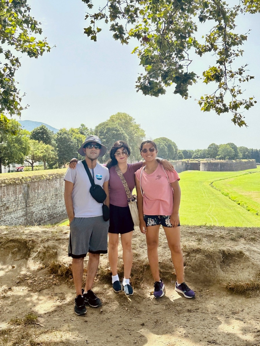 Family moment on the historic walls of Lucca, Italy, surrounded by green trees and open countryside views.