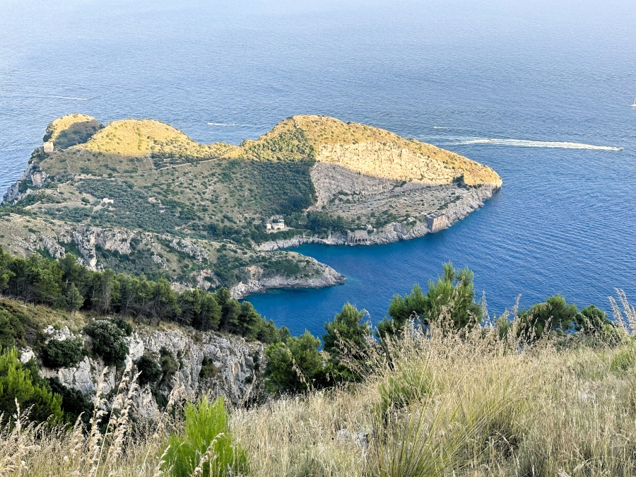 A high viewpoint overlooking the turquoise inlet of Baia di Ieranto from the Sorrento Peninsula hike, with rocky cliffs, Mediterranean scrub, and deep blue sea.