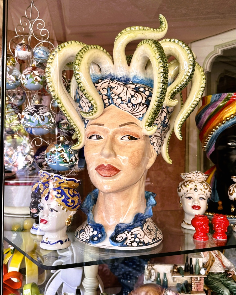 Handcrafted ceramic sculpture resembling a Medusa-inspired head with ornate details and tentacle-like hair, displayed in a Sorrento artisan shop.