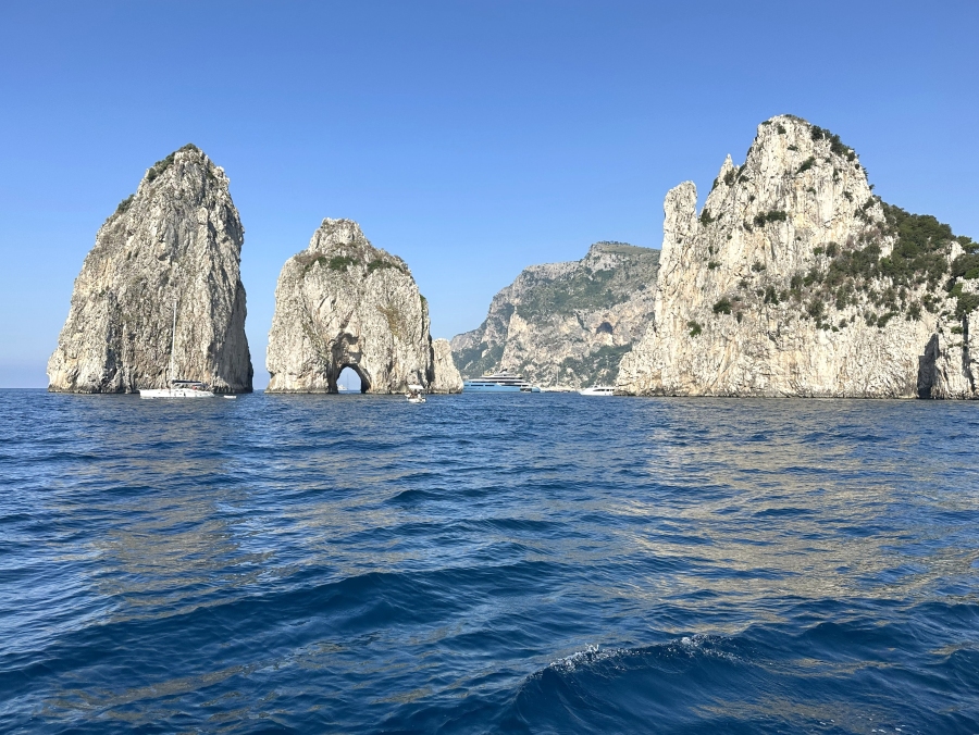 View of the Faraglioni rock formations in Capri seen from a boat on a clear summer day