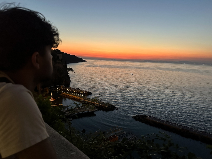 Young man watching a golden sunset over the Sorrento Marina and coastline after returning from a sunset hike.