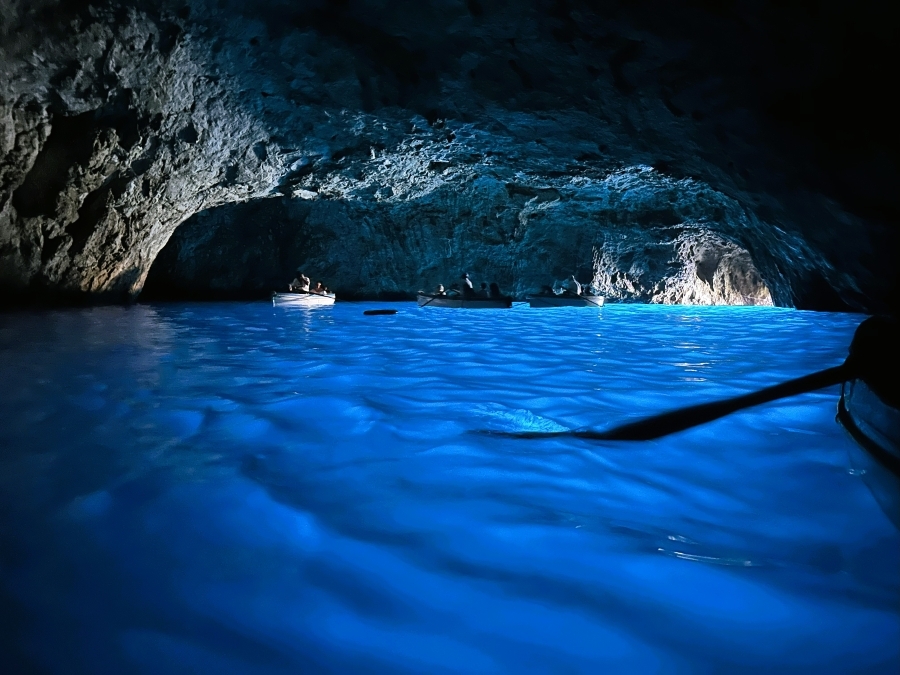 Inside the Blue Grotto in Capri, with boats floating on the cave’s radiant blue water illuminated by sunlight