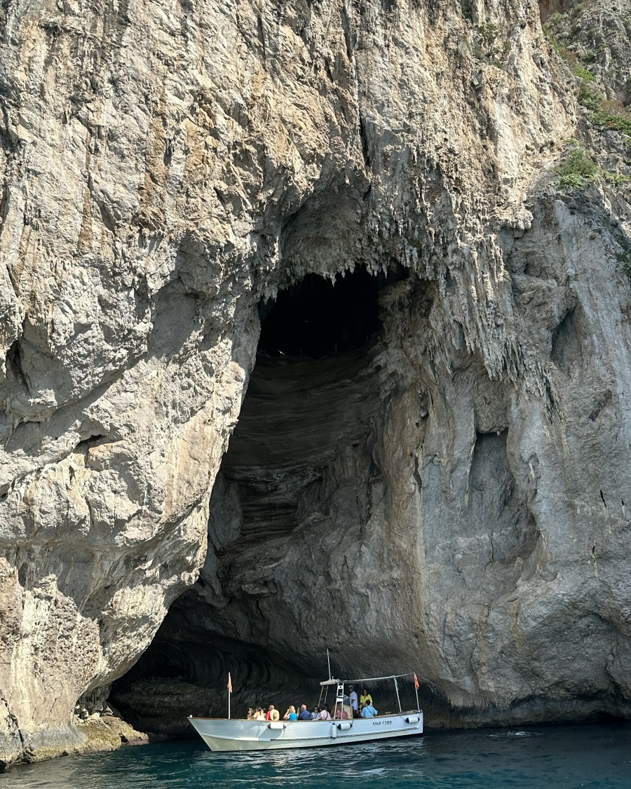 Boat entering a large sea cave along the rocky coastline of Capri during an island boat tour.